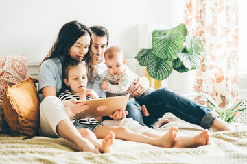 Family with two daughter using tablet, laptop for playing game watching movies, relaxing at home for lifestyle concept