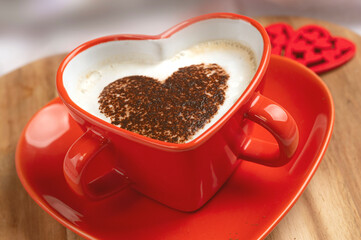 . Heart shaped cup filled with hot drink on the bed. Concept for Valentine's Day or Honeymoon.
