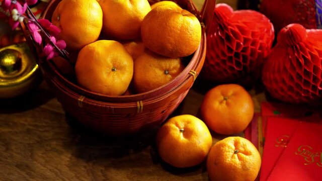 Basket of mandarin oranges and  Chinese new year festival decorations ,red packet,plum blossom ,ingot and lantern on red background.