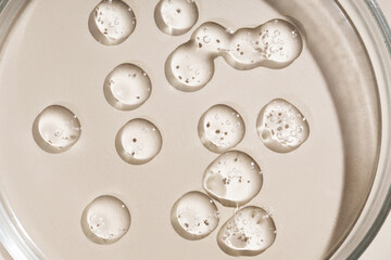 Cosmetic drops. Drops of liquid transparent gel with bubbles on a brown background.