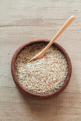 Brown rice in a wooden bowl with wooden or bamboo spoon