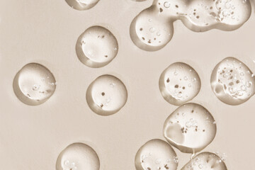 Cosmetic drops. Drops of liquid transparent gel with bubbles on a brown background.