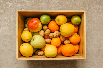 Fresh fruits in a wooden box. Mix of fruits. A lot of vitamins. Variety of fruits in wooden crate box. Fruits rich in vitamin C. Healthy vegetarian eating.Lemon, apples, nuts, orange for snack.
