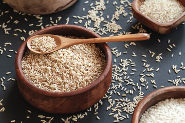 Set of different types of rice and cereals in wooden bowls and bamboo spoon