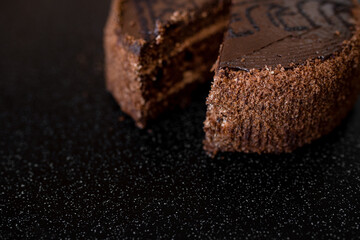 Piece of cake. Sliced tasty chocolate cake. Chocolate cake with a cut piece on black background, closeup.