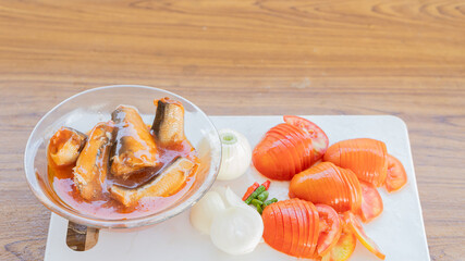 Canned fish and tomatoes with onions cut on a cooking board.