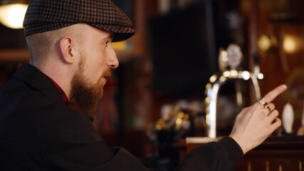 Man ordering drink sitting at counter in moder bar