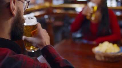 Close up of waiter in safety gloves serving glasses of beer to customers in pub