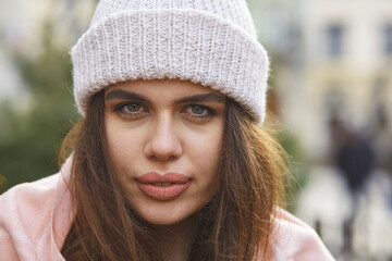 close up winter portrait of a young woman in a white hat