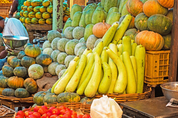Gourds and various fruits for sale in an indoor Indian market