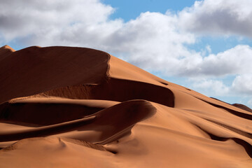 Fototapeta na wymiar Golden sand dune 7 and white clouds on a sunny day in the Namib desert. Fantastic place for travelers