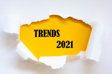 Top view of white torn paper and TRENDS 2021 text on yellow background.