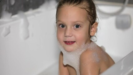 Happy child having fun playing with foam in the bathroom