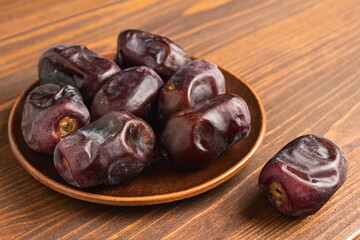 Dried organic date fruits in a plate on wooden table