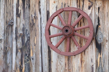 An old wooden wheel hangs on a plank wall
