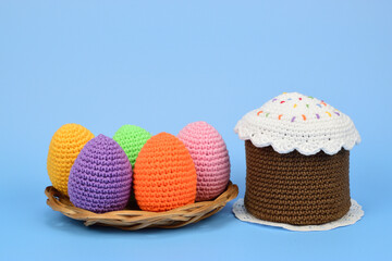 Knitted easter eggs and cake isolated on light blue background