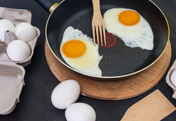 Fried eggs cooking process. Two fried eggs in a pan and raw eggs
