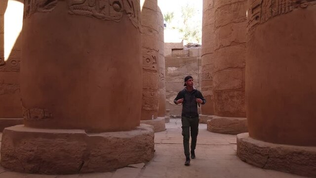 A young man visiting the Karnak temple and walking between the old columns