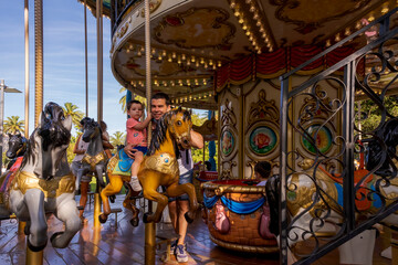 Fototapeta na wymiar Boy with his father on top of a carousel horse in Santander.