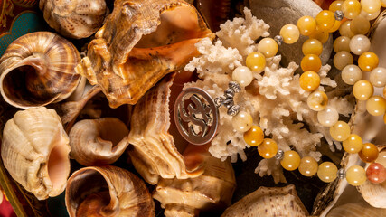 Buddhist prayer beads Mala lying on the sea rocks surrounded by sea shells. close-up