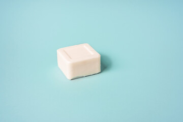 White bar of soap lying on a blue background, minimalistic concept