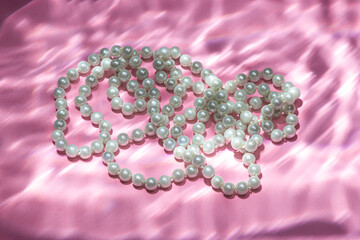 White beads on a pink background. Sun glare from the water on the background.