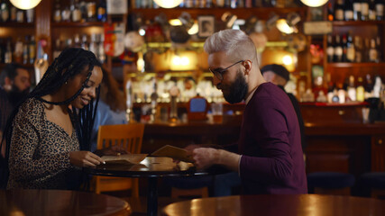Multiethnic couple reading menu in modern restaurant