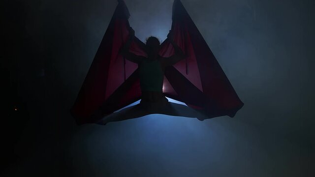 Girl Hanging Upside Down in Hammock. Lady Doing Inverted Pigeon Pose in Hammock. Sport concept for the whole family