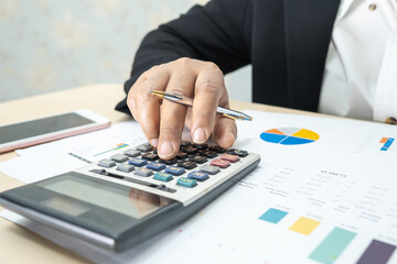 Asian accountant working and analyzing financial reports project accounting with chart graph and...