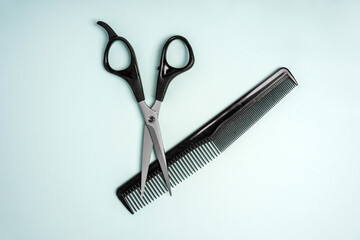 Hairdressing tools scissors and comb lie on a blue background