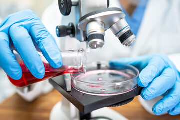 Asian scientist biochemist or microbiologist working research with a microscope in laboratory. For protect outbreak Coronavirus Covid19, bacteria and germs.