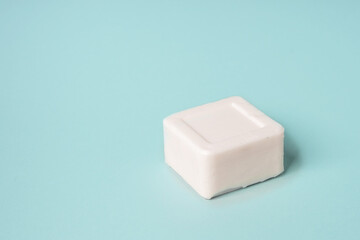 White bar of soap lying on a blue background, minimalistic concept
