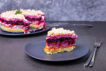 Herring salad under a fur coat. Traditional Russian multilayered salad from herring, beets, potatoes, carrots and eggs. Close-up, grey background.