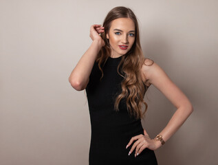 Fototapeta premium Beautiful young woman with long and healthy wavy hair posing in dress showing healthy figure and wearing wrist watch