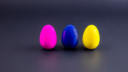 three multi-colored small eggs on a black background