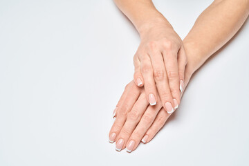 Obraz premium Beautiful Female Hands with French manicure over light grey background