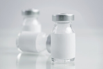 Close up image of vaccine or injection bottles with blank white label.  Vial bottle mockup. Science, vaccination, immunization, health care and medical concept. 