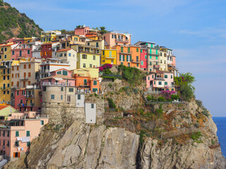 Fototapeta na wymiar View of Manarola. Colorful old buildings on a steep cliff, close up. Traditional Italian cityscape. The Cinque Terre area is a popular tourist destination. Province La Spezia, Liguria region, Italy.