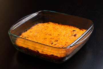 Carrot casserole with raisins in a glass pan on a dark wooden surface