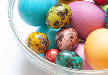 Colorful painted Easter eggs in the glass bowl on the white background. Close up