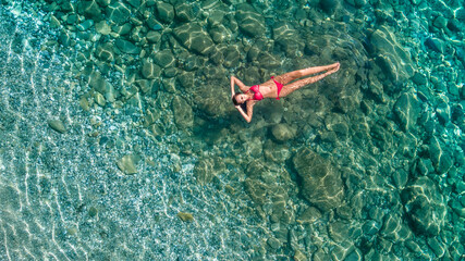 Aerial view of swimming woman in clear azure water, blue lagoon.  Spain, Roses.