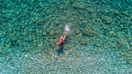 Aerial view of swimming woman in clear azure water, blue lagoon.  Spain, Roses.