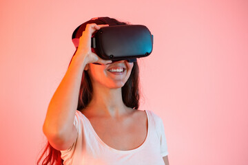 Young woman with with headset on eyes smiling from close up. Happy female in virtual reality with digital equipment on head. Brunette exploring in cyberspace.