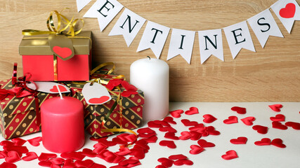 Happy Valentines day white flags garland, gifts with metallic ribbons, bows and labels with hearts, wax candles, red silk hearts on wood background. Love, Valentine's, romantic, rendezvous template
