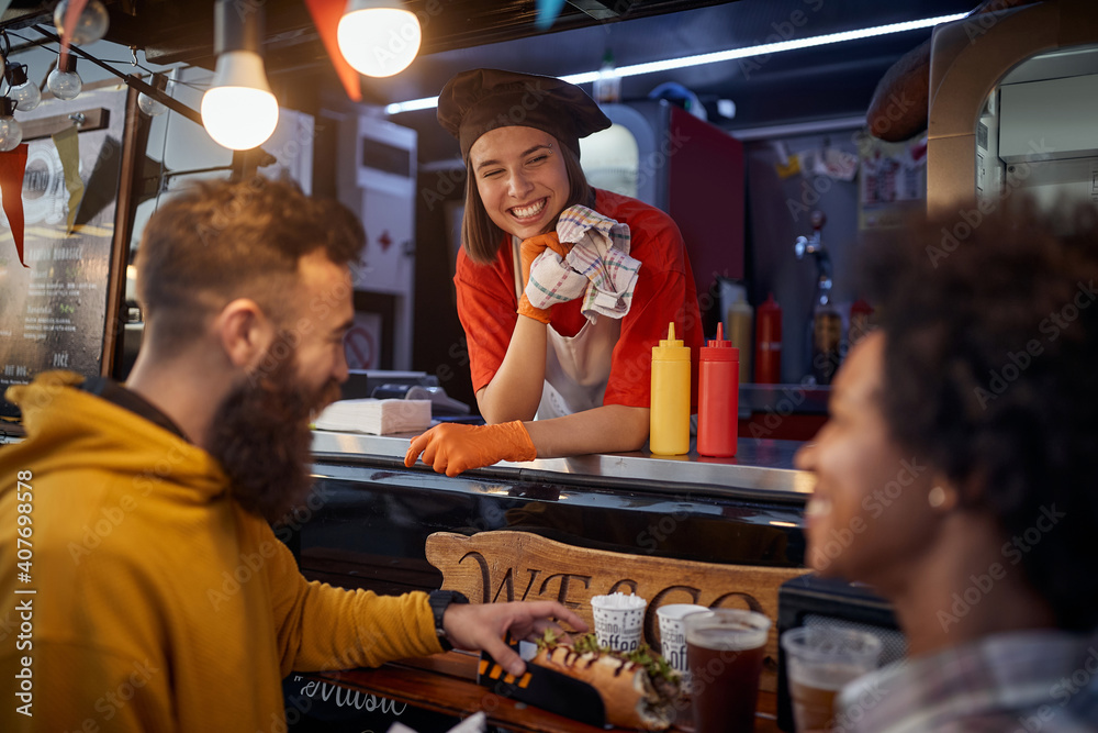 Wall mural friends having a snack and a chit chat with an employee in fast food service, smiling