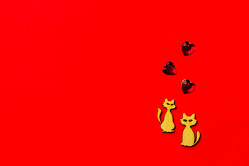 Two enamored animals, wooden cats with a crystal heart on a red background. Copy space. Valentine's Day and wedding concept
