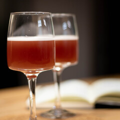 Wine glass with cocktail on wood table and book in background