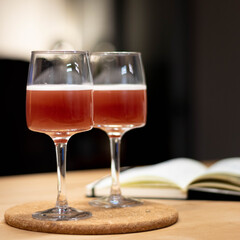 Wine glass with cocktail on wood table and book in background
