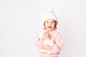 a little girl in winter clothes holds a rabbit on a white background. New year's concept, space for text