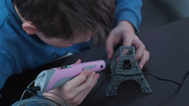 a boy makes a 3 d model with a pen. assembling the layout of the Elfin tower. classes with rebonk.